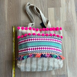 NWT. Pom Pom boho style tote. Lined w/ zip pocket & snap closure. Bright colors.